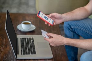 Płatności online. Mężczyzna siedzący przy laptopie i płacący kartą kredytową online