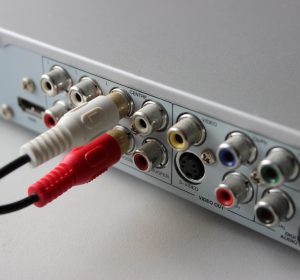 Dwa wtyczki RCA podłączone do gniazd wideo wyjściowych tylnego panelu odtwarzacza multimedialnego