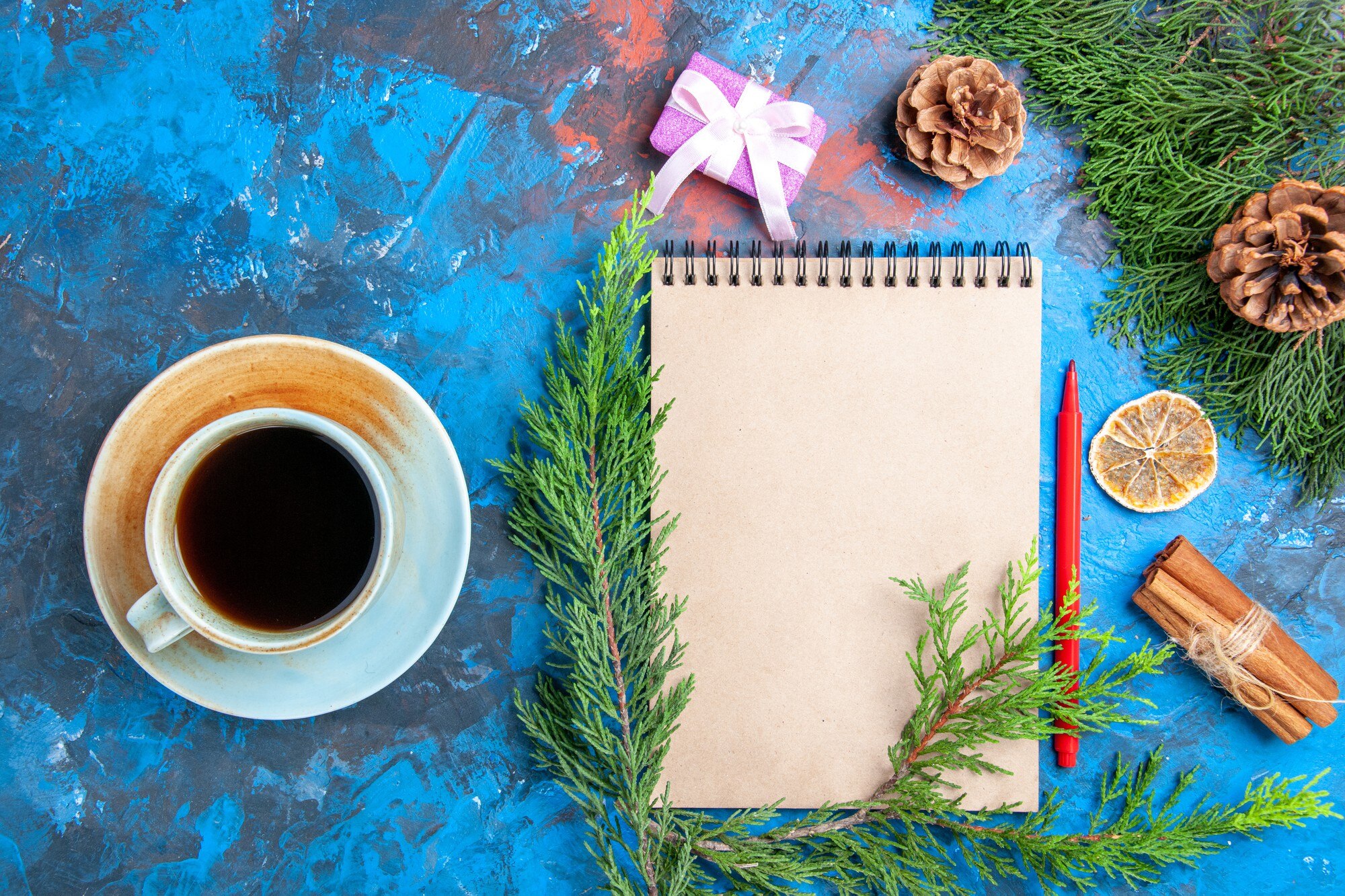 Widok z góry notatnik gałęzie sosny czerwony ołówek filiżanka herbaty na niebieskim tle