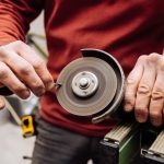 Młody mężczyzna w czerwonym swetrze robi coś za pomocą narzędzi przemysłowych