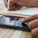 Zbliżenie bizneswoman za pomocą aplikacji kalkulatora na smartfonie i pisania w planner