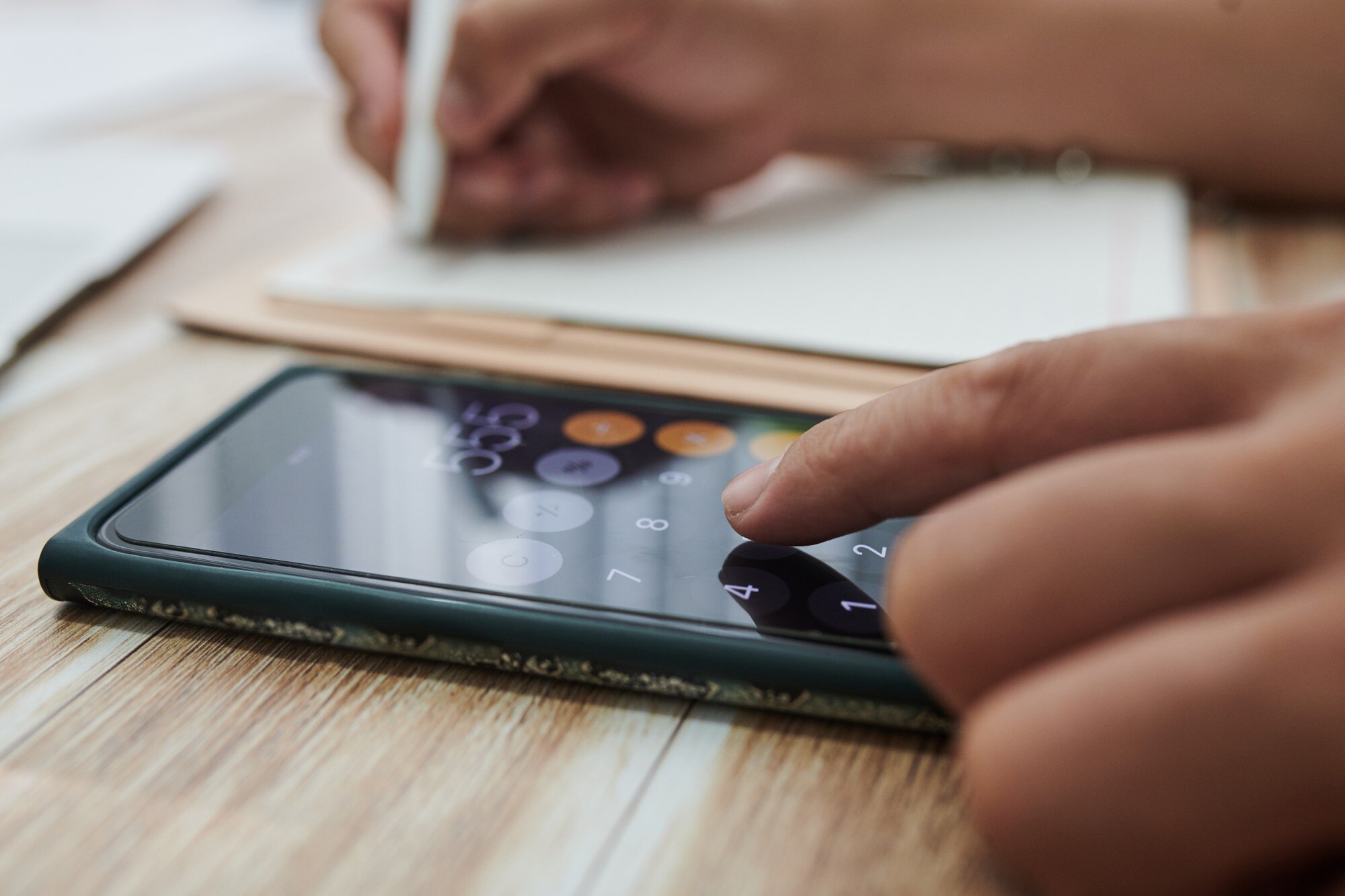 Zbliżenie bizneswoman za pomocą aplikacji kalkulatora na smartfonie i pisania w planner