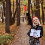 Szczęśliwa dziewczyna trzyma tablet z życzeniami dobrego dnia i czerwoną filiżanką kawy