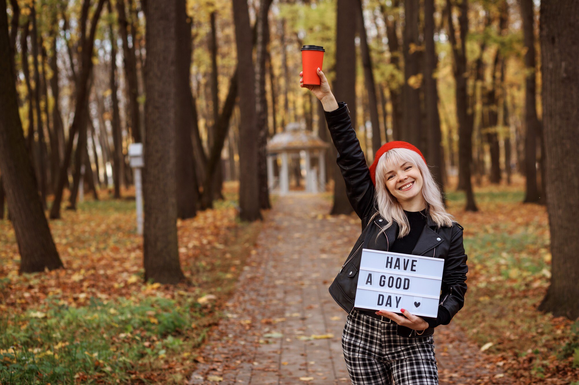 Szczęśliwa dziewczyna trzyma tablet z życzeniami dobrego dnia i czerwoną filiżanką kawy