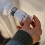 Kobieta reguluje ogrzewanie na grzejniku baterii w domu w zimnej porze roku ręce close-up