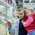 Ojciec trzyma małą dziewczynkę w pobliżu stoiska z orzechami na rynku