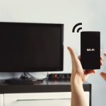 Ręka trzymająca smartfon na tle salonu