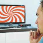 Starszy mężczyzna z praniem mózgu. hipnotyczna spirala na ekranie telewizora. Młody człowiek zahipnotyzowany fałszywymi informacjami na ekranie monitora. Fałszywe wiadomości w Internecie. widz przed telewizorem.