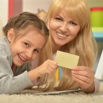 Portret dziewczynki bawiącej się z matką na komputerze w domu