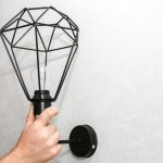 Człowiek posiadający lampę w ręce. Instalacja elektryczna. Nowoczesny projekt loftu. Renowacja w pomieszczeniu. Prace konserwacyjne.