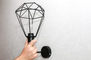 Człowiek posiadający lampę w ręce. Instalacja elektryczna. Nowoczesny projekt loftu. Renowacja w pomieszczeniu. Prace konserwacyjne.