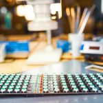 Duży mikroskop elektronowy i panel wskaźników świetlnych LED są ułożone na płycie, aby przygotować się do badań komponentów elektronicznych w laboratorium