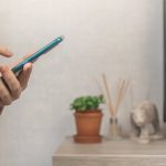 Kobieta za pomocą smartfona w domu, wysyłanie wiadomości lub przeglądanie sieci społecznościowych koncepcja zdjęcie w tle