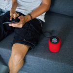 Ojciec i córka testują inteligentny głośnik bezprzewodowy, kontrolują urządzenia domowe za pomocą poleceń głosowych, siedzą na kanapie w domu, koncepcja inteligentnego domu