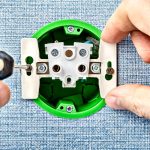 Technik wymienia zepsute gniazdko elektryczne.