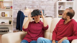 Siostrzeniec uczy babcię korzystania z zestawu do wirtualnej rzeczywistości w salonie