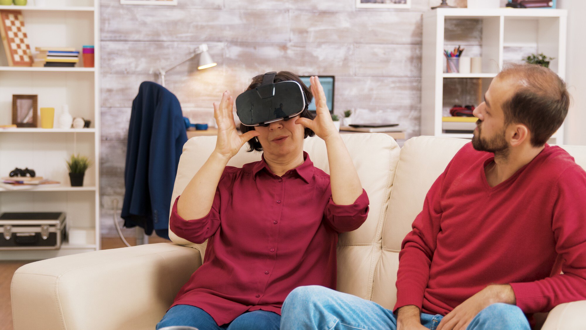Siostrzeniec uczy babcię korzystania z zestawu do wirtualnej rzeczywistości w salonie
