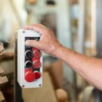 Jedna osoba naciskająca przycisk w fabryce drewna