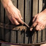 Prasa do wina z czerwonym moszczem i śrubą śrubową Ręce winiarza z bliska