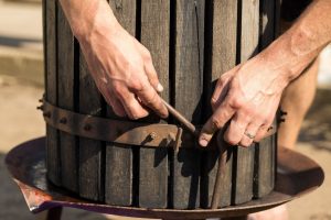 Prasa do wina z czerwonym moszczem i śrubą śrubową Ręce winiarza z bliska