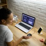 Widok z góry na dentystę-lekarza siedzącą przed laptopem z panoramicznym zdjęciem rentgenowskim ludzkich zębów i udzielającą pacjentowi konsultacji online przez wideorozmowę na temat leczenia stomatologicznego