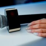 Mikrofon na białym stole z pustą płytką na napis obok kobiecej dłoni. Zdjęcie wysokiej jakości