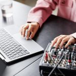 Zbliżenie młodej kobiety korzystającej z laptopa podczas konfigurowania sprzętu nagrywającego w przestrzeni kopii studyjnej