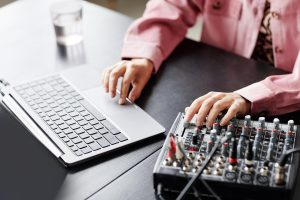 Zbliżenie młodej kobiety korzystającej z laptopa podczas konfigurowania sprzętu nagrywającego w przestrzeni kopii studyjnej