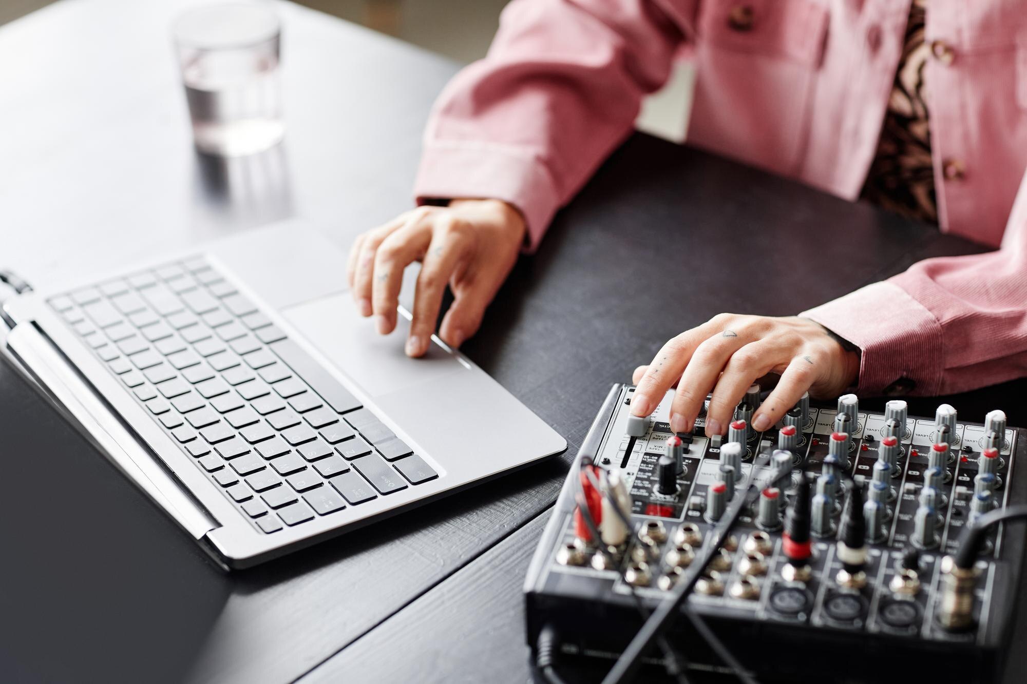 Zbliżenie młodej kobiety korzystającej z laptopa podczas konfigurowania sprzętu nagrywającego w przestrzeni kopii studyjnej