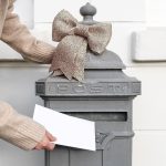 Ręka trzyma list i wkłada do staromodnej skrzynki pocztowej w pobliżu domu, doręczenie na pocztę