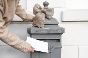 Ręka trzyma list i wkłada do staromodnej skrzynki pocztowej w pobliżu domu, doręczenie na pocztę