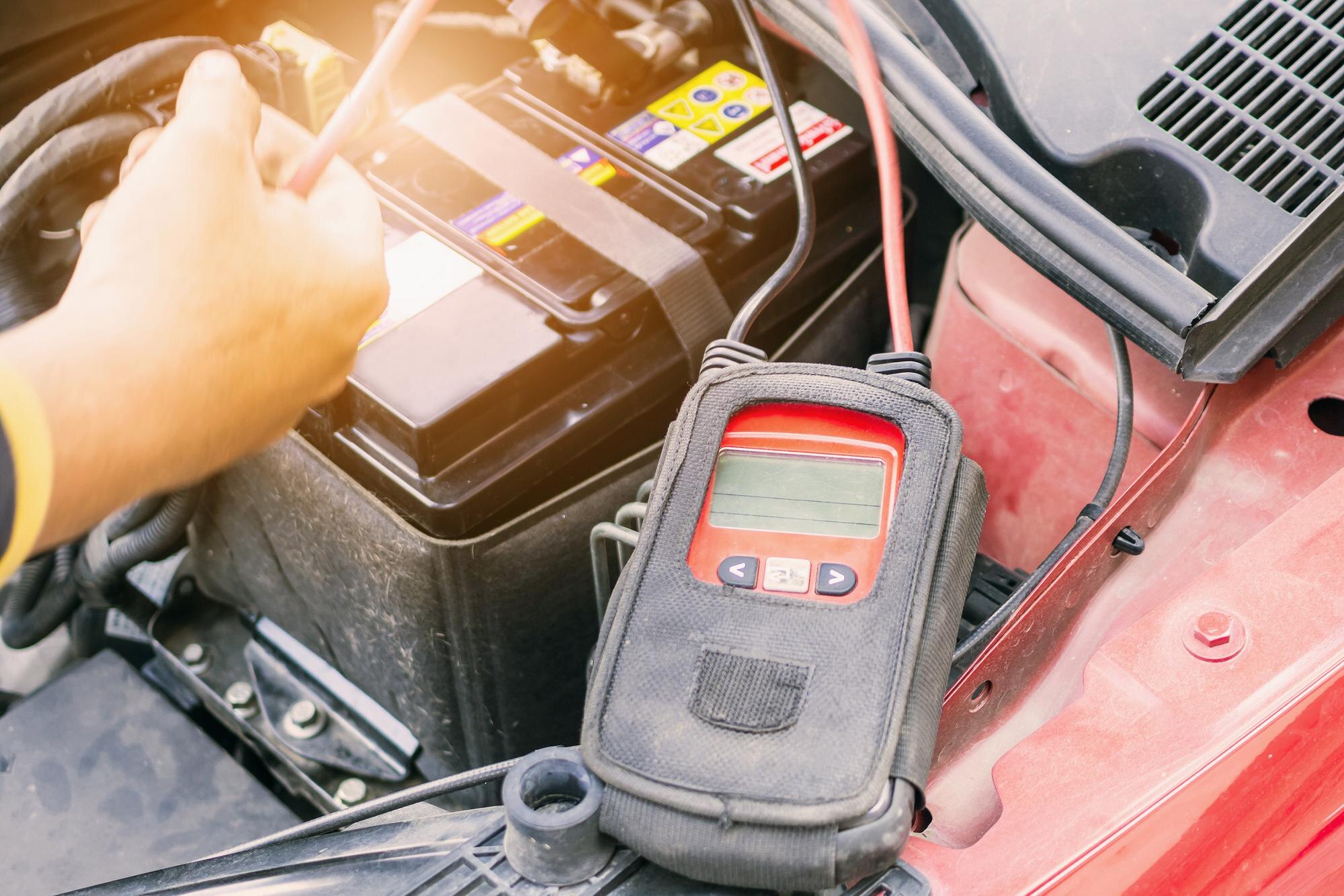 Mechanik samochodowy używa woltometru do sprawdzenia poziomu napięcia akumulatora samochodowego