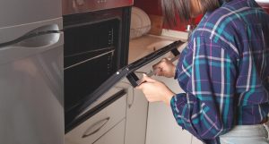 Kobieta zamyka drzwiczki piekarnika w kuchni.