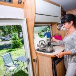 Kobieta, gotowanie w kamperze, wnętrze kampera. Rodzinne wakacje w podróży, wakacje w kamperze, wakacje w przyczepie kempingowej.