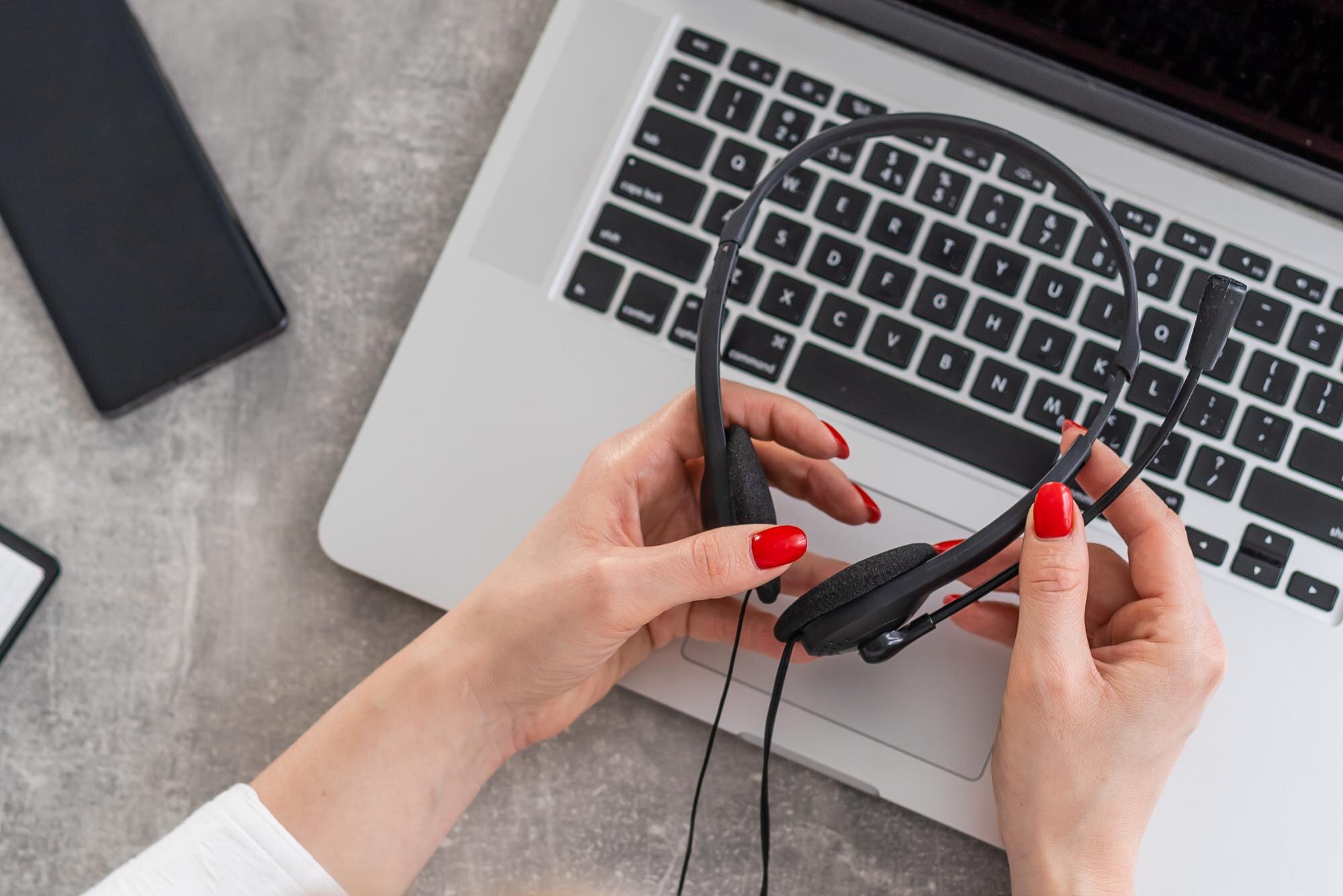 Słuchawki, telefon i laptop na białym stole na rozmytym tle