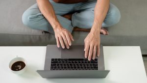 Koncepcja technologiczna Mężczyzna w brązowej koszulce koncentrujący się na swoim laptopie komputerowym