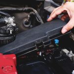 Mechanik wyjmuje skrzynkę bezpieczników z samochodu