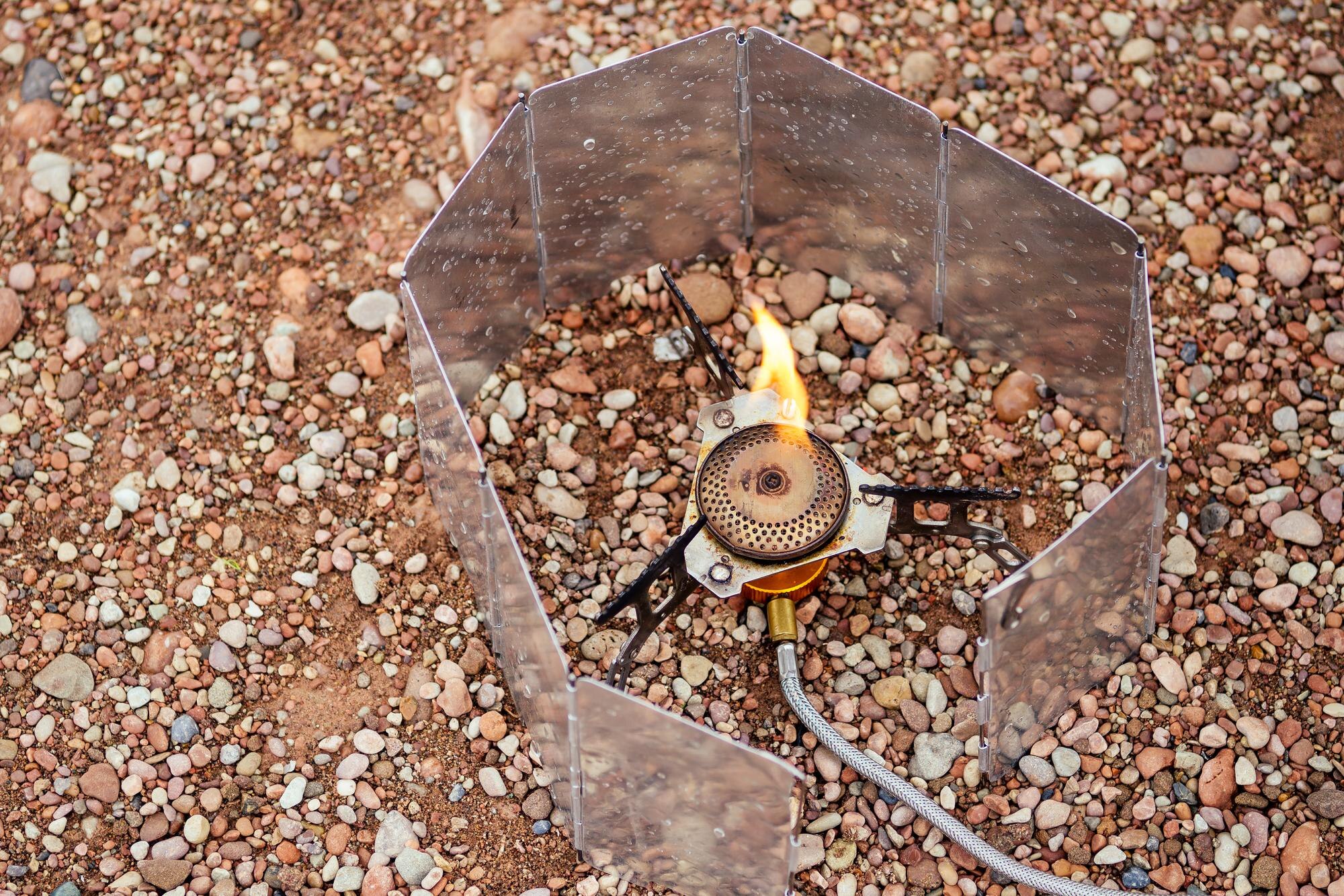 Patelnia z owsianką stoi na palniku gazowym Piec kempingowy Na tle rzeki