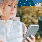 Kobieta jest w jesiennym parku z parasolką i telefonem Jesienna atmosfera