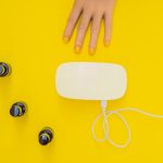 Pielęgnacja dłoni kobiety wypielęgnowane paznokcie w promieniach lampy UV utwardzanie lakieru żelowego małe zdobienia paznokci i manicure