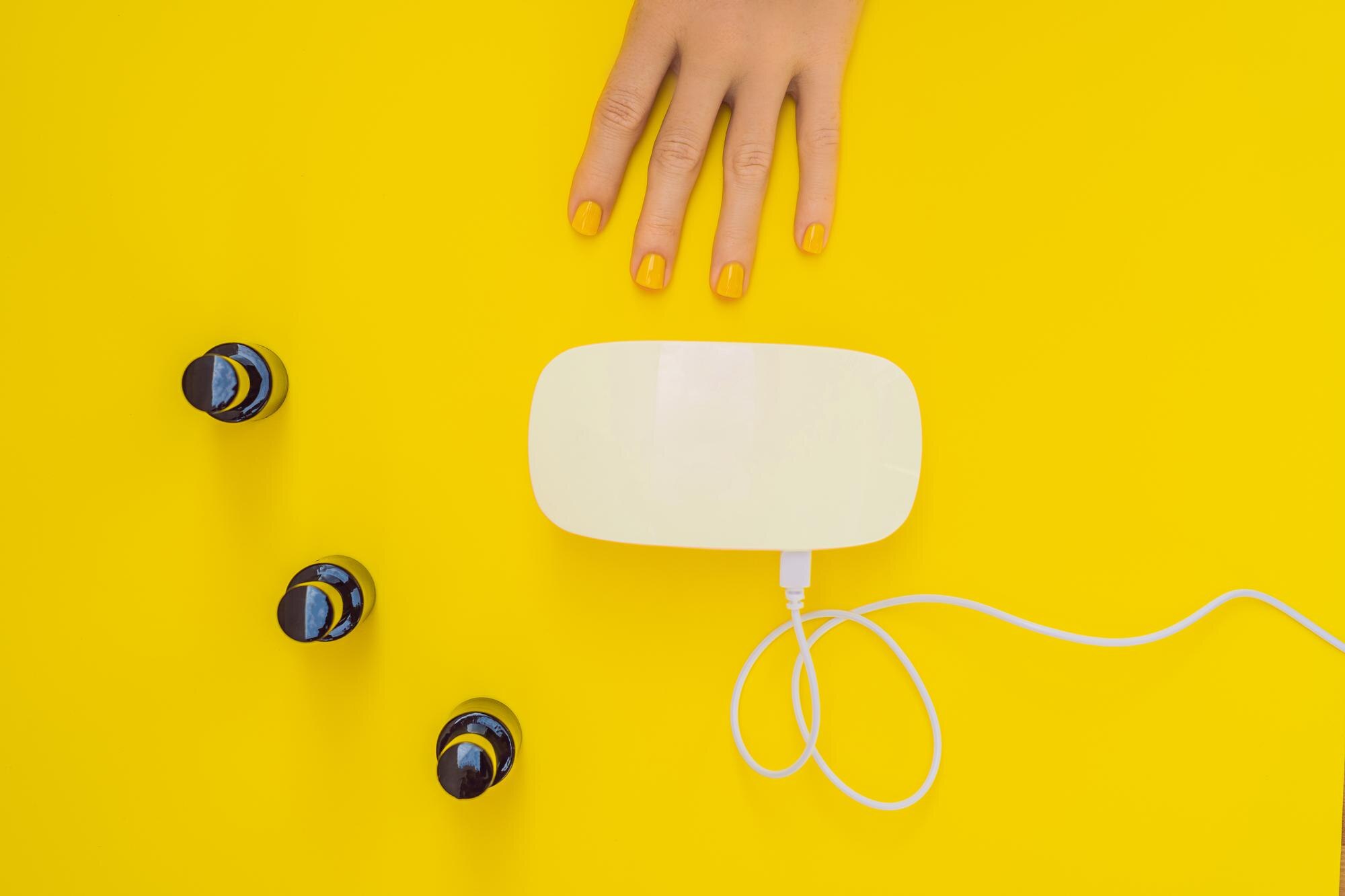 Pielęgnacja dłoni kobiety wypielęgnowane paznokcie w promieniach lampy UV utwardzanie lakieru żelowego małe zdobienia paznokci i manicure