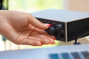 Nierozpoznawalne ręce młodej kobiety dostosowujące ustawienia dźwięku miksera audio w domowym studio z bliska