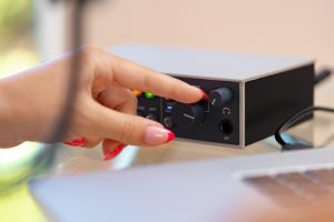 Nierozpoznawalne ręce młodej kobiety dostosowujące ustawienia dźwięku miksera audio w domowym studio z bliska