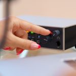 Nierozpoznawalne ręce młodej kobiety dostosowujące ustawienia dźwięku miksera audio w domowym studio z bliska