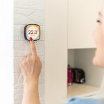 Panel sterowania termostatem inteligentnego domu na ścianie do zimowego baneru temperatury w domu. Energooszczędne dotknięcie ręką w celu regulacji temperatury ogrzewania w salonie.