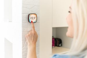 Panel sterowania termostatem inteligentnego domu na ścianie do zimowego baneru temperatury w domu. Energooszczędne dotknięcie ręką w celu regulacji temperatury ogrzewania w salonie.