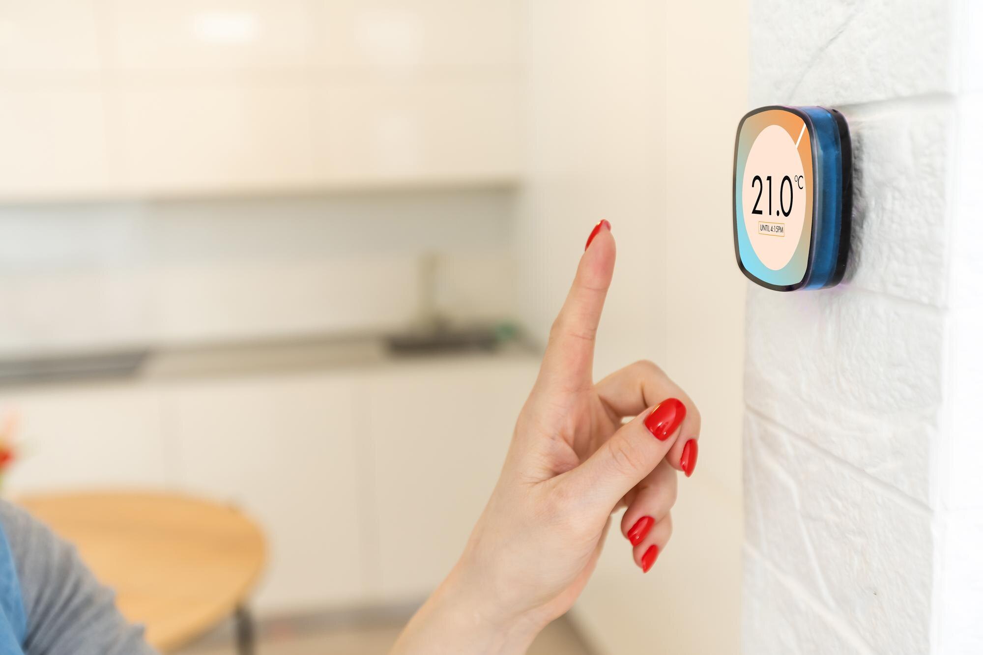 Inteligentny dom cyfrowy termostat dotykowy kobieta dotykająca ekranu dotykowego, aby dostosować temperaturę ogrzewania w ścianie salonu.