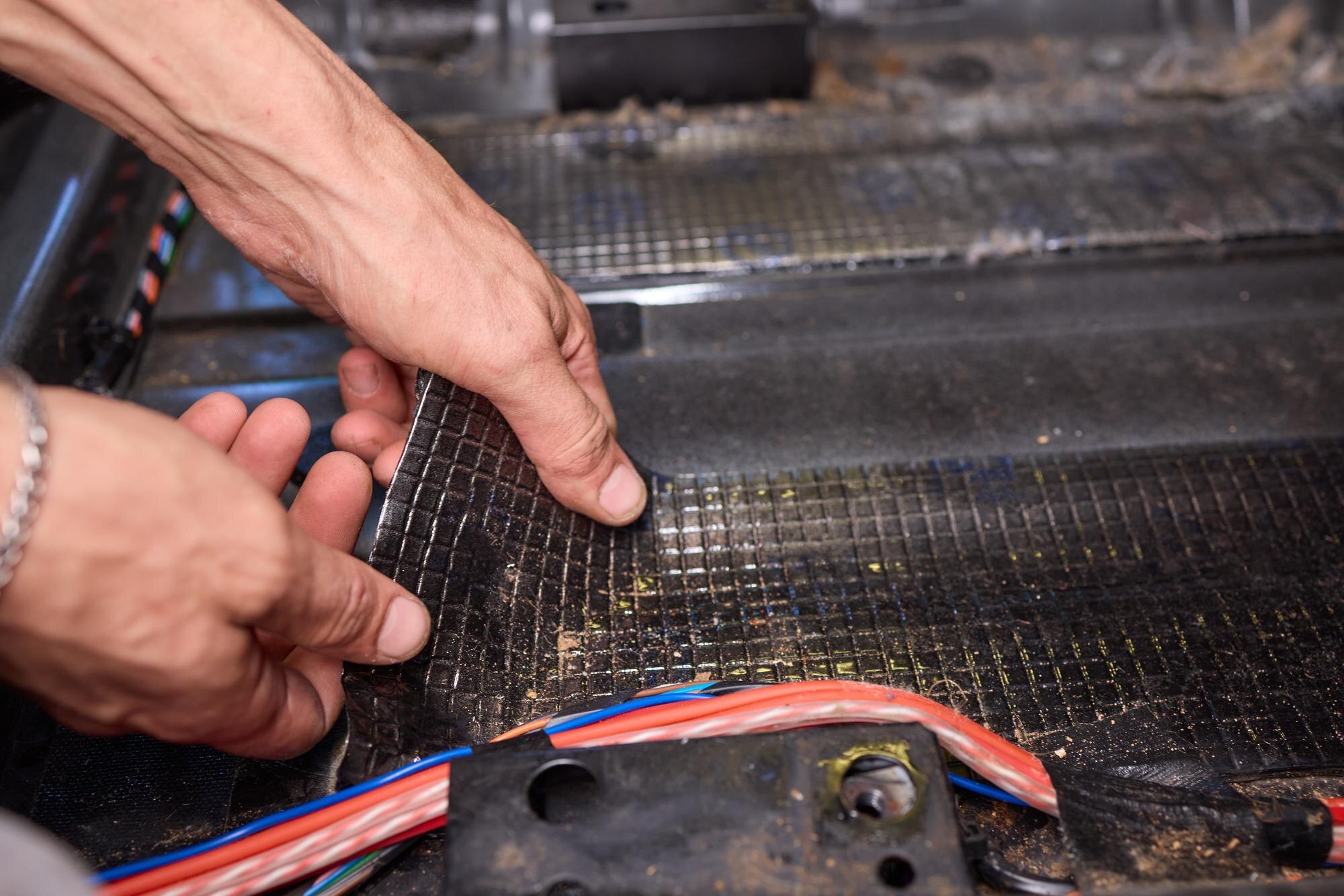 Pracownik serwisowy instaluje materiał dźwiękoszczelny we wnętrzu samochodu