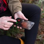 Dziewczyna siedzi na kłodzie w lesie i odbiera telefon od bliskiej osoby Podróże trekkingowe i piesze