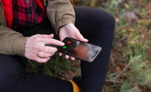 Dziewczyna siedzi na kłodzie w lesie i odbiera telefon od bliskiej osoby Podróże trekkingowe i piesze